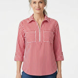 Silver-haired woman wearing a red and white striped half-zip popover blouse with dual chest pockets and rolled sleeves,