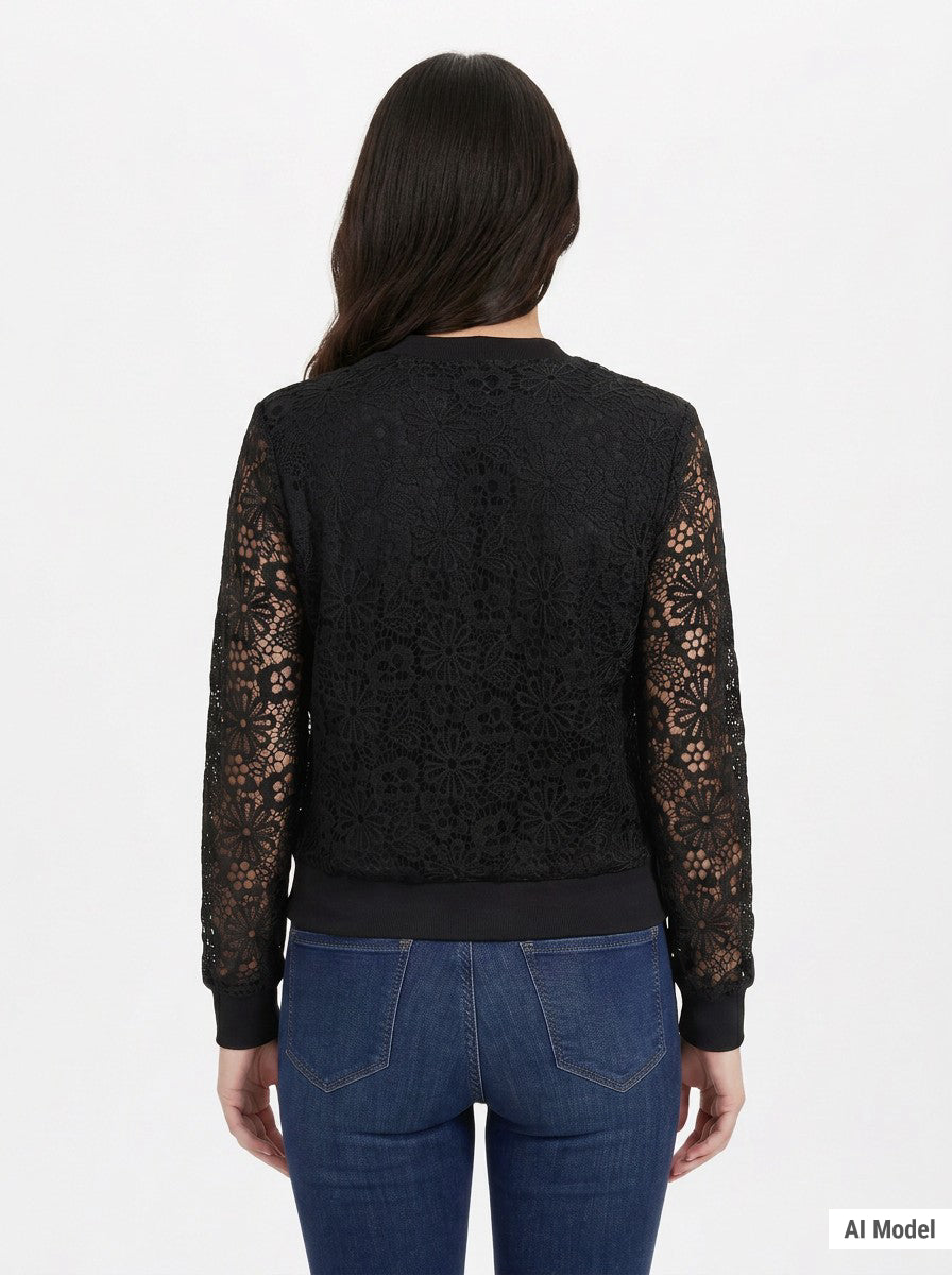 Woman shown from behind wearing a black floral lace bomber jacket with sheer sleeves and ribbed hem, paired with blue jeans.