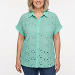 Older woman with gray bob wearing a mint green short-sleeve lace eyelet button-front blouse with collar, paired with blue
