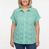 Older woman with gray bob wearing a mint green short-sleeve lace eyelet button-front blouse with collar, paired with blue