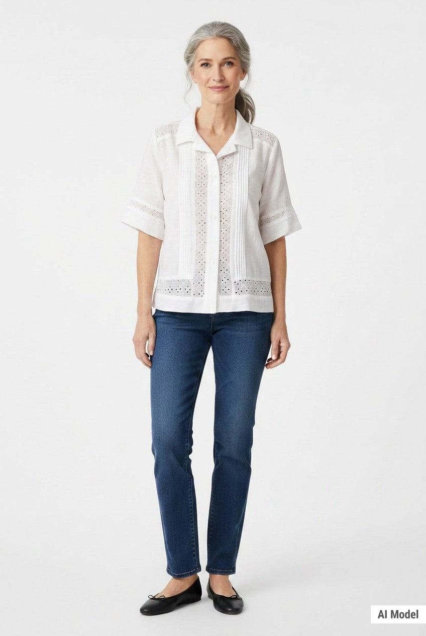White short-sleeve button-front blouse with eyelet insets and pintuck detail, worn by a woman with gray hair, front view.