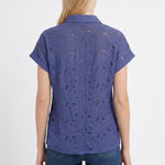Blonde female model shown from back wearing a patriot blue short-sleeve eyelet button-back blouse with cuffed sleeves,