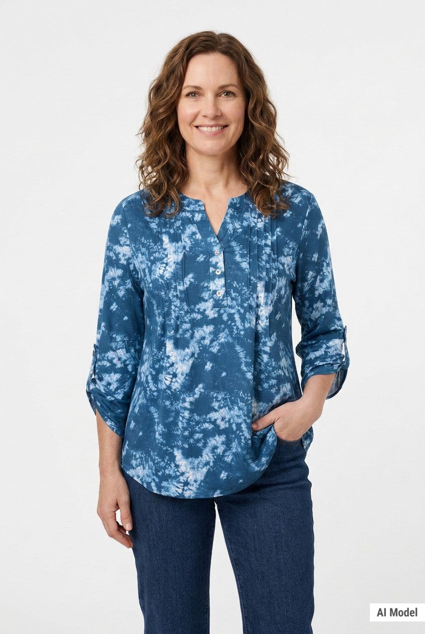 Woman wearing a blue tie-dye popover top with Y-neckline, pintucks, button placket, and roll-tab 3/4 sleeves; front view,