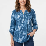 Woman wearing a blue tie-dye popover top with Y-neckline, pintucks, button placket, and roll-tab 3/4 sleeves; front view,