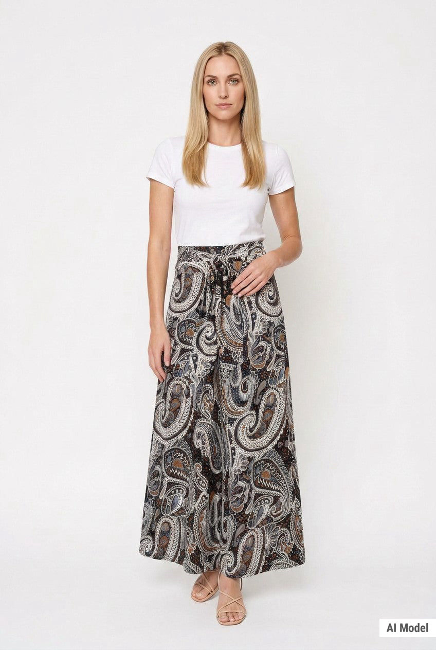 Blonde female model wearing a black and brown paisley maxi skirt with a sash waist tie, front view, paired with a white tee