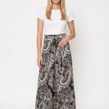 Blonde female model wearing a black and brown paisley maxi skirt with a sash waist tie, front view, paired with a white tee