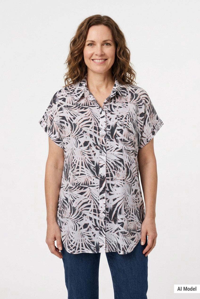 Woman wearing a short rolled-sleeve button-front blouse in black, white, and pink palm leaf print, with a collar and chest