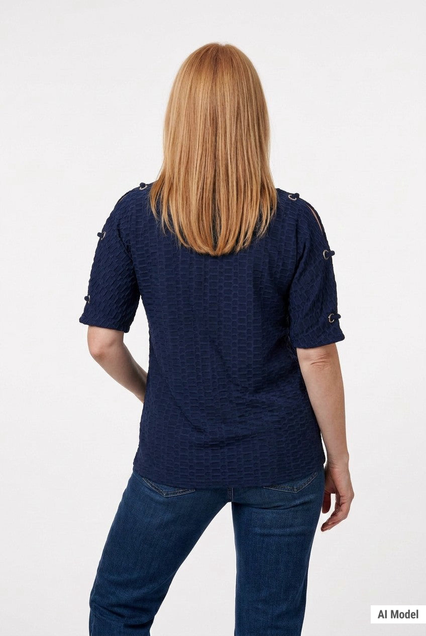 Back view of a woman with long blonde hair wearing a navy honeycomb-texture short-sleeve tunic with grommet details on