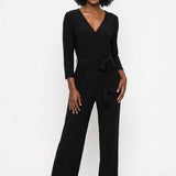 Black wide-leg jumpsuit with V-neck wrap bodice, 3/4 sleeves, and self-tie waist belt; female model, front view, full length.