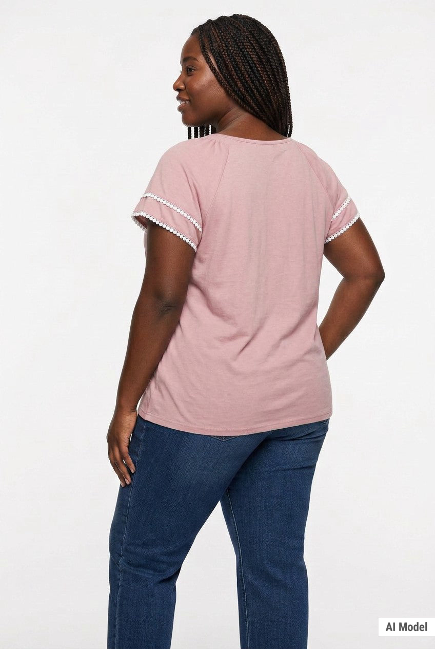 Plus-size woman with braids shown from the back wearing a dusty pink short-sleeve blouse with white lace trim on sleeves,