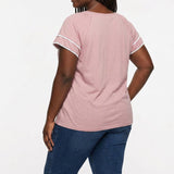Plus-size woman with braids shown from the back wearing a dusty pink short-sleeve blouse with white lace trim on sleeves,