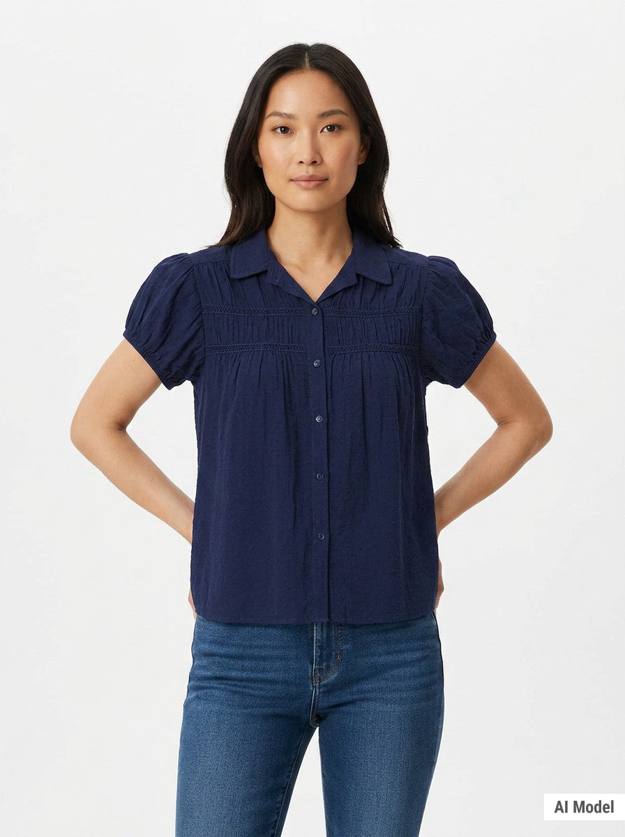 Woman wearing a navy blue short puff-sleeve button-front blouse with ruched yoke, lace trim details, and camp collar; front