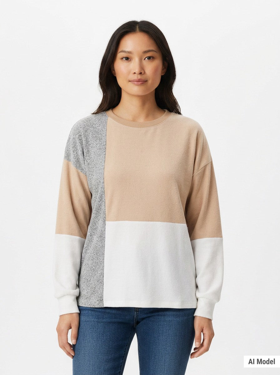Woman wearing a colorblocked pullover with beige, white, and gray panels, crew neck, and long sleeves; front view, waist up.