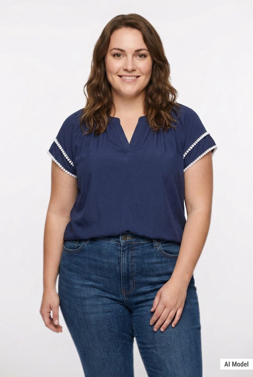 Navy blue split-neck popover blouse with white lace trim on flutter sleeves, worn by a plus-size woman with blue jeans,