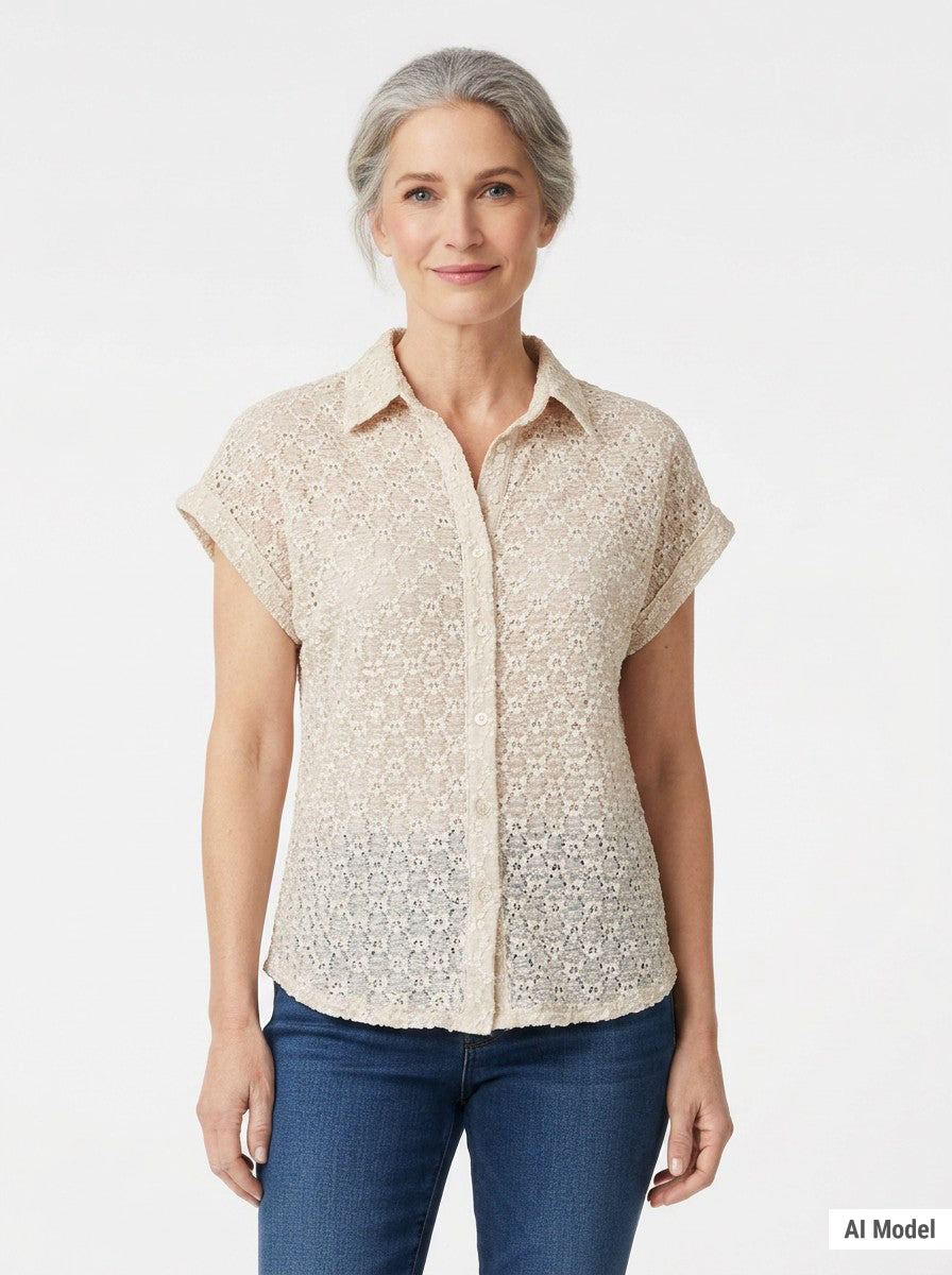 Front view of a woman wearing a beige floral lace button-front blouse with a collar and cuffed cap sleeves, paired with blue