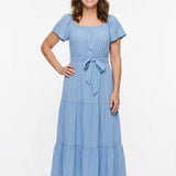 Light blue short-sleeve tiered maxi dress with square neckline and self-tie waist belt, worn by a woman with brown hair,