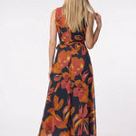 Blonde model shown from behind wearing a sleeveless navy chiffon maxi dress with bold orange and red floral print and