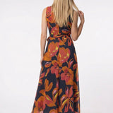 Blonde model shown from behind wearing a sleeveless navy chiffon maxi dress with bold orange and red floral print and