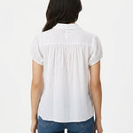 White short-sleeve button-front blouse with gathered yoke and puff sleeves, shown from the back on a dark-haired woman
