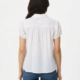 White short-sleeve button-front blouse with gathered yoke and puff sleeves, shown from the back on a dark-haired woman