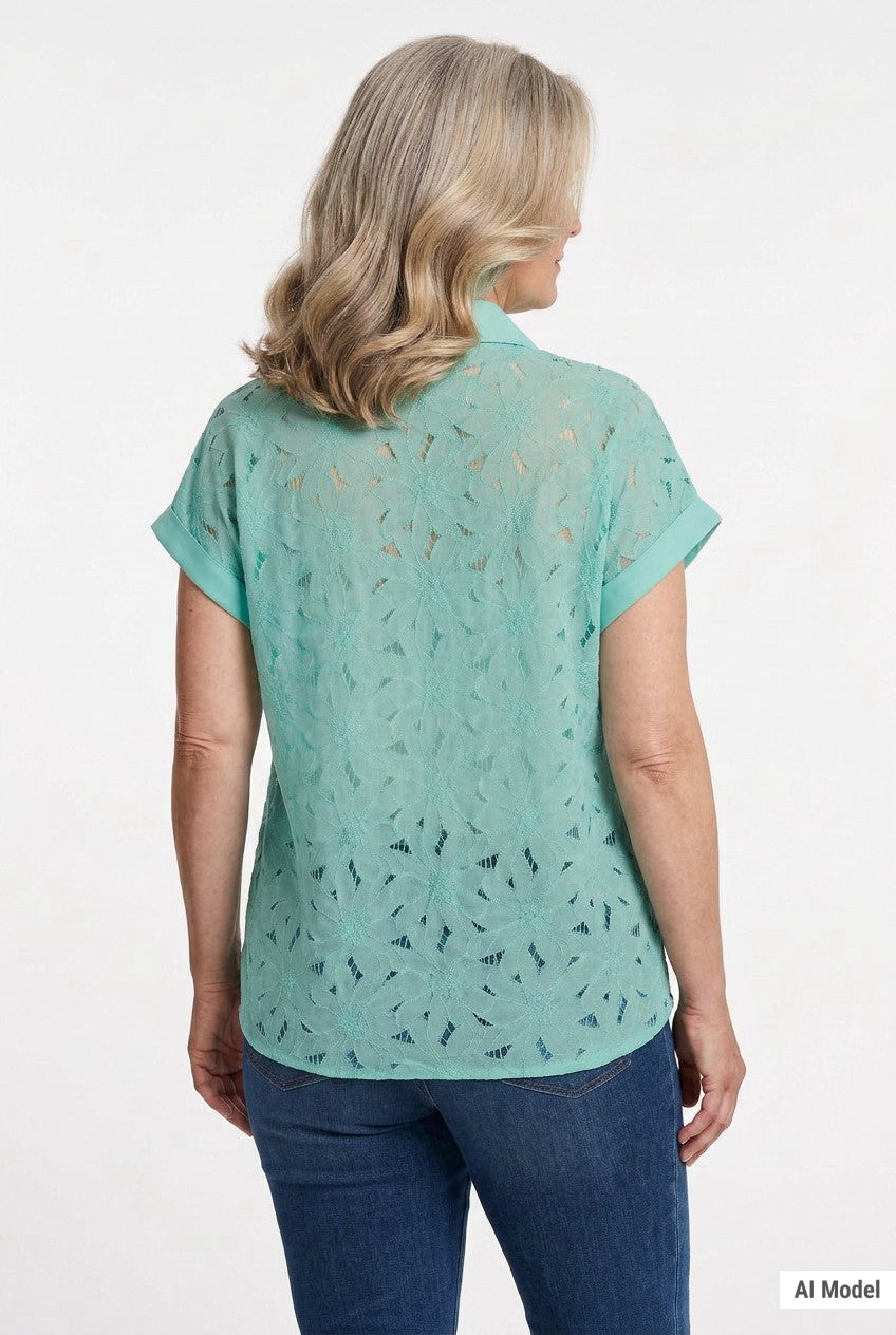 Blonde woman wearing a mint green short-sleeve eyelet blouse with floral cutwork detailing and collar, paired with dark