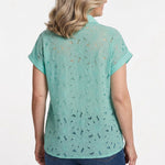 Blonde woman wearing a mint green short-sleeve eyelet blouse with floral cutwork detailing and collar, paired with dark