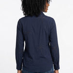 Woman wearing a navy long-sleeve button-front blouse with tonal palm tree eyelet embroidery, shown from the back, paired