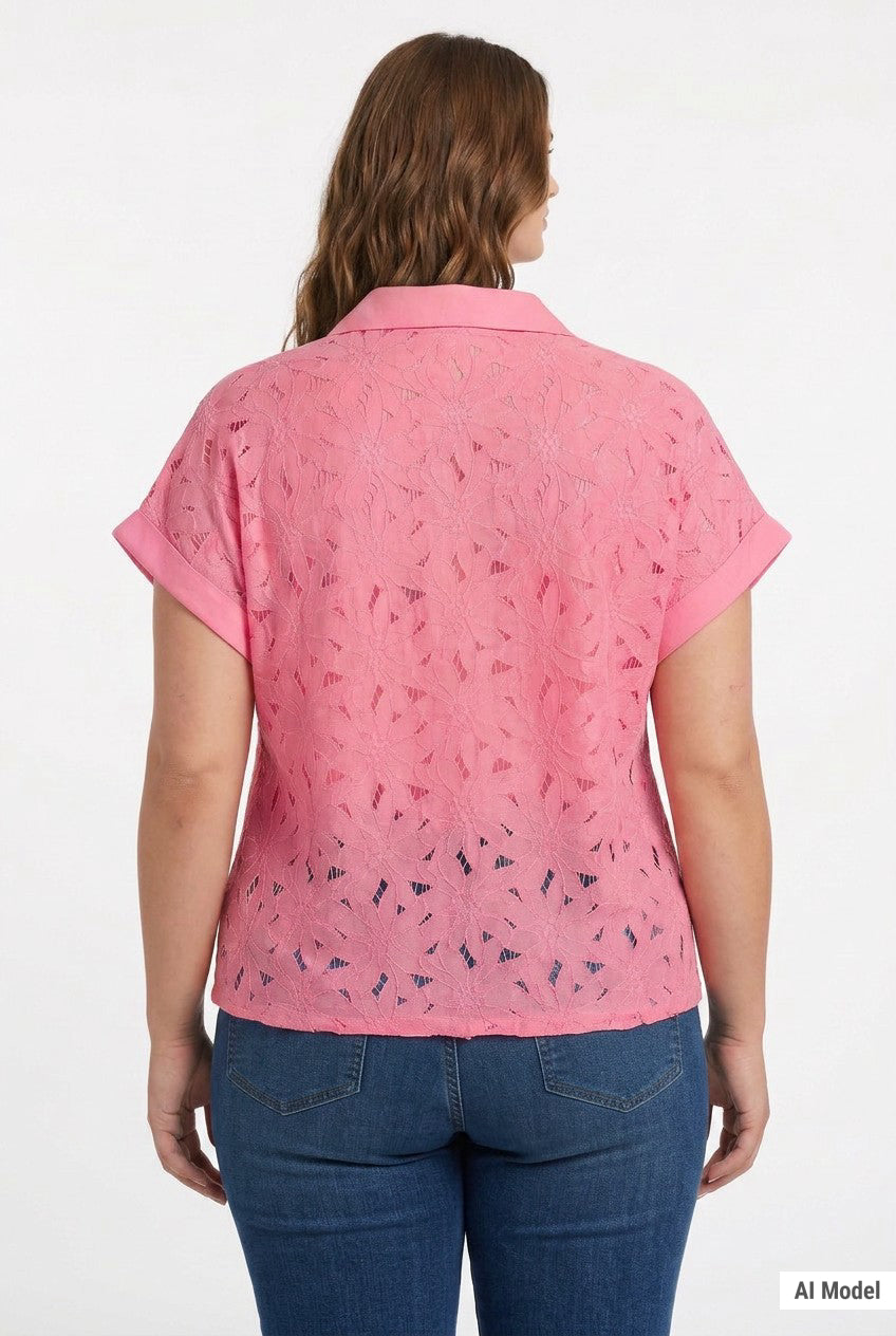 Plus-size model wearing a pink short-sleeve eyelet button-front blouse with collar and cuffed sleeves, paired with dark