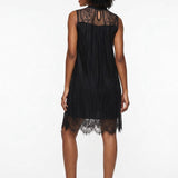 Woman wearing a black sleeveless lace shift dress with sheer high neck, scalloped hem, and keyhole back, shown from behind