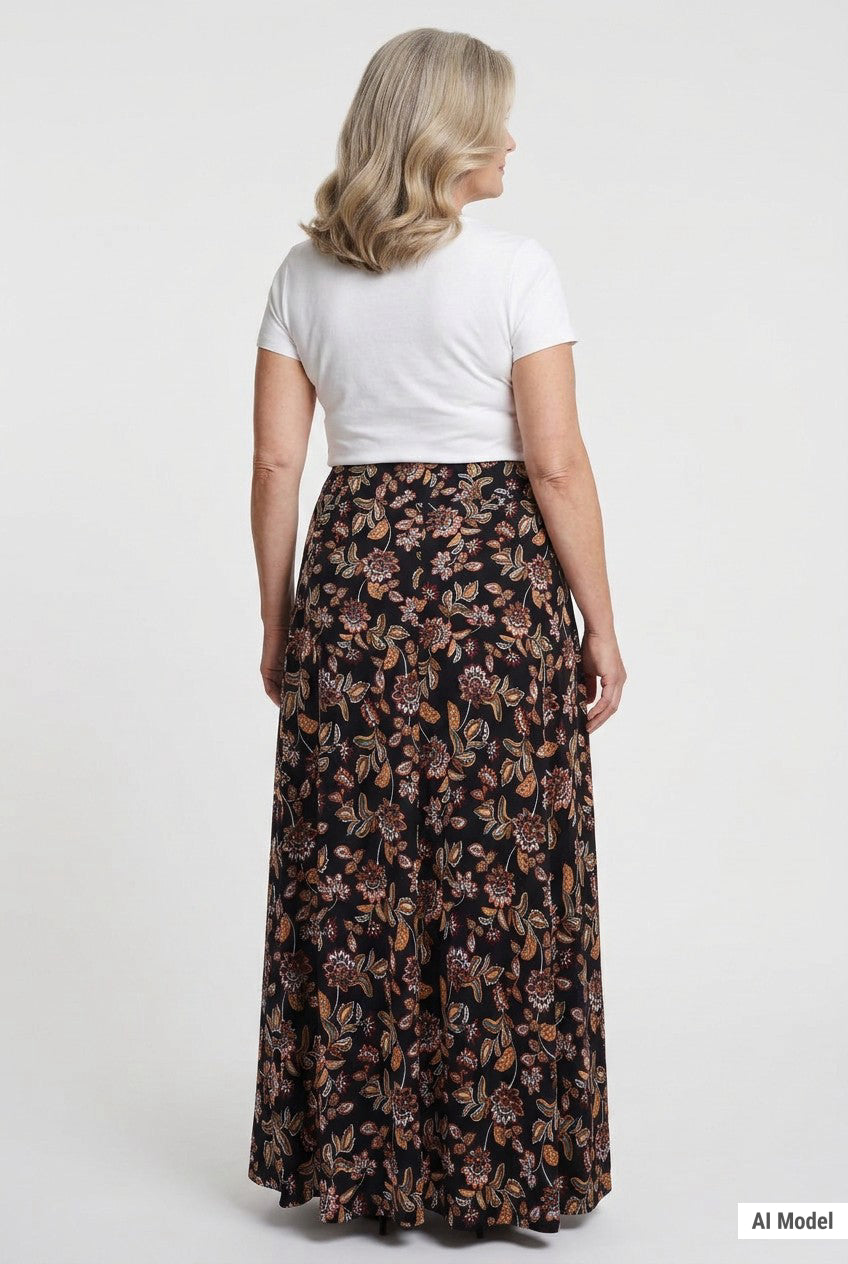 Plus-size maxi skirt in black with earth-tone floral print, back view, worn by a blonde woman with a white short-sleeve tee.