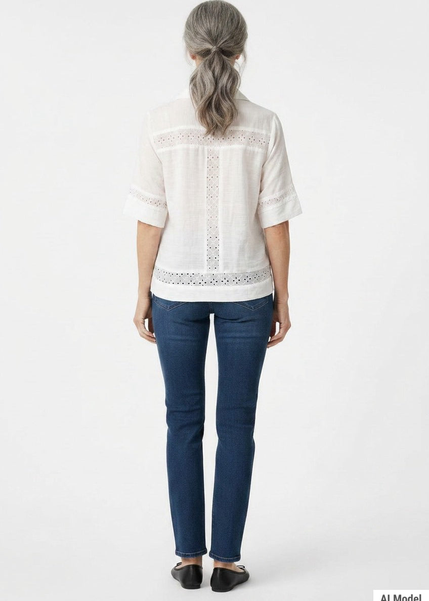Back view of a woman with gray hair wearing a white short-sleeve eyelet-inset blouse with lace trim panels, paired with dark