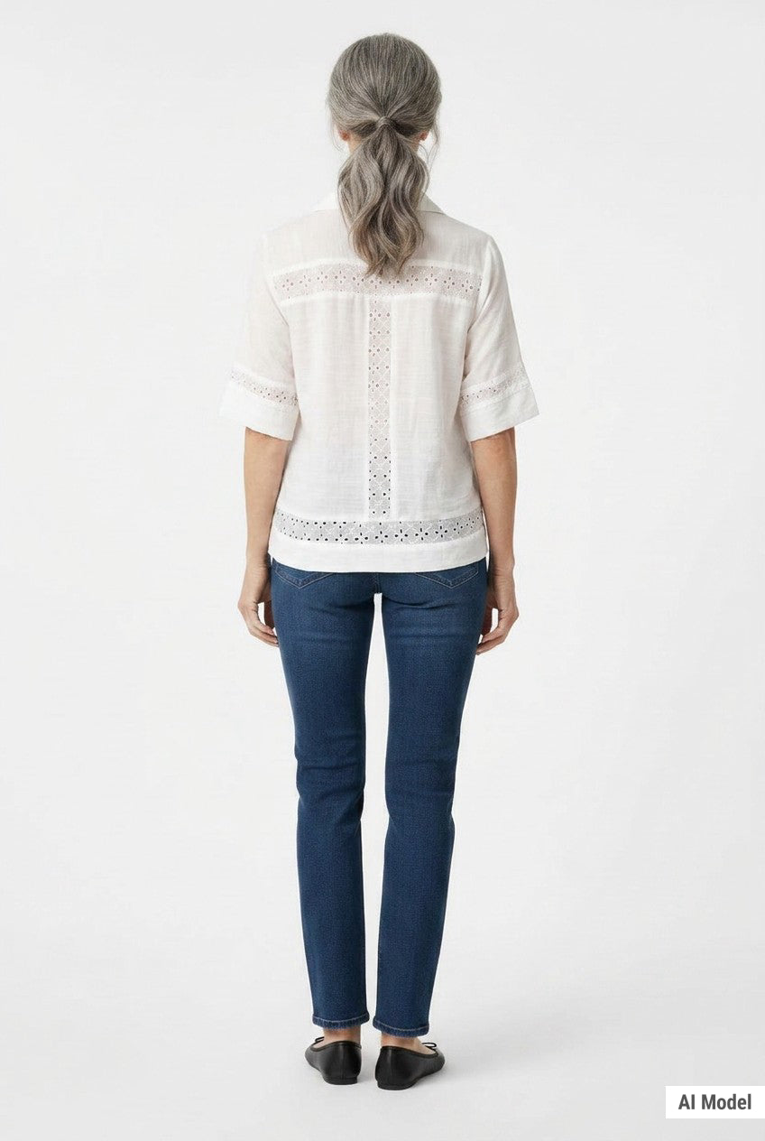 Back view of a woman with gray hair wearing a white short-sleeve eyelet-inset blouse with lace trim panels, paired with dark