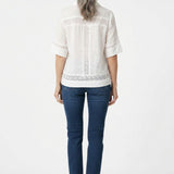 Back view of a woman with gray hair wearing a white short-sleeve eyelet-inset blouse with lace trim panels, paired with dark