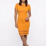 Mustard yellow short-sleeve sheath dress with mesh insets at boat neckline and hem, worn by a brunette woman, front view.