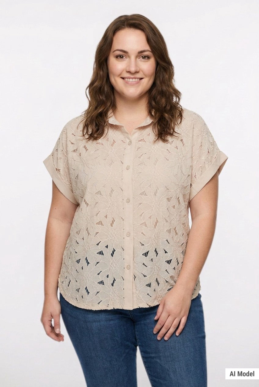 Plus-size woman wearing a beige short-sleeve eyelet button-front blouse with floral cutwork pattern; front view, waist up.