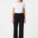 Black pull-on pants with elastic waistband and wide-leg silhouette on a gray-haired woman, front view, full length.