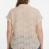 Plus-size model wearing a beige short-sleeve eyelet blouse with collar and cuffed sleeves, paired with blue jeans; rear view.