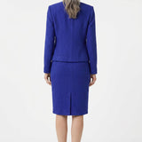 Back view of a woman with gray hair wearing a royal blue textured knit jacket and knee-length pencil skirt set with a back