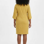 Woman wearing a mustard yellow sheath dress with 3/4 petal sleeves trimmed with pearl details; back view, knee length.