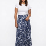 Navy and white paisley-print knit maxi skirt with sash waist tie, worn by a brunette woman, full front view.