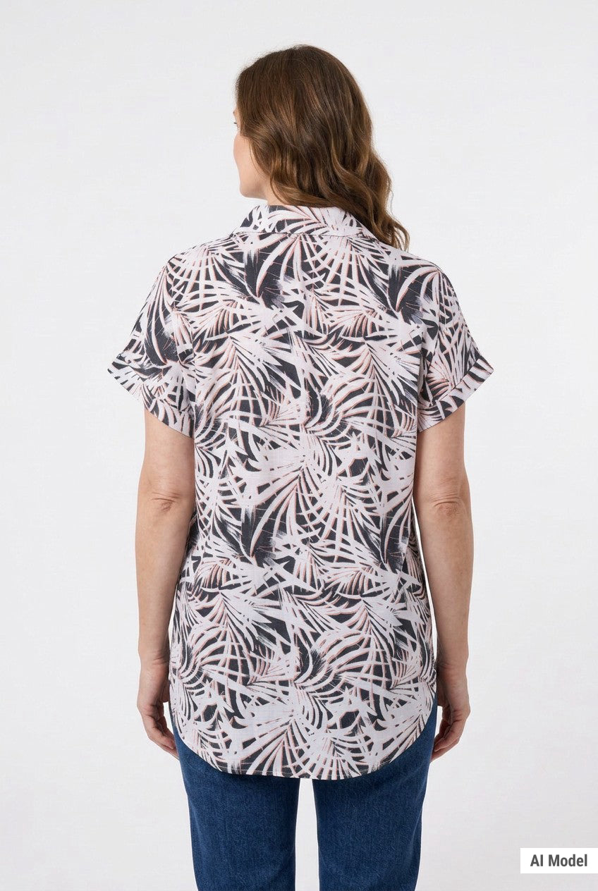 Back view of a woman wearing a short rolled-sleeve button-front blouse in black and blush palm leaf print, paired with blue