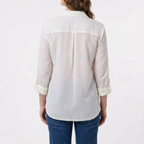 Woman's back view showing ivory windowpane button-front blouse with rolled 3/4 sleeves, back pleat, and blue jeans.