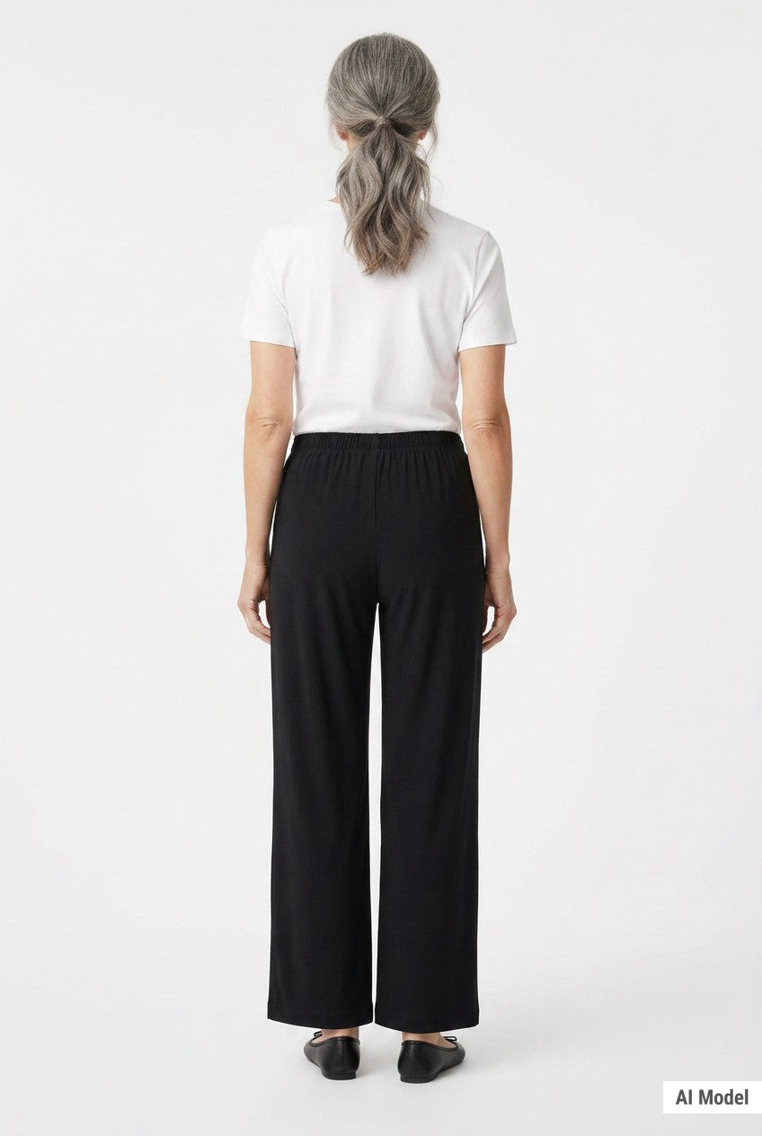 Back view of black wide-leg pull-on pants with elastic waistband on a gray-haired woman wearing a white tee, full-length