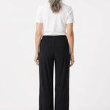 Back view of black wide-leg pull-on pants with elastic waistband on a gray-haired woman wearing a white tee, full-length