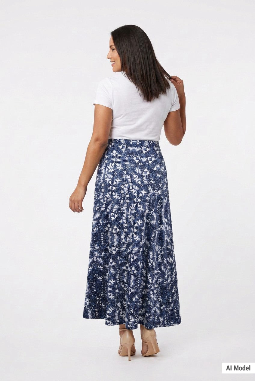 Back view of a dark-haired model wearing a navy blue floral-print knit maxi skirt with a flared hem, paired with a white tee
