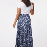 Back view of a dark-haired model wearing a navy blue floral-print knit maxi skirt with a flared hem, paired with a white tee