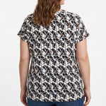 Plus-size woman shown from back wearing a short-sleeve pullover top with navy, white, and taupe abstract print, paired with