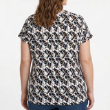 Plus-size woman shown from back wearing a short-sleeve pullover top with navy, white, and taupe abstract print, paired with