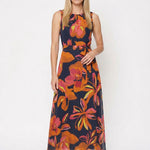 Blonde female model in a navy sleeveless chiffon maxi dress with bold orange and pink floral print, self-tie waist belt,