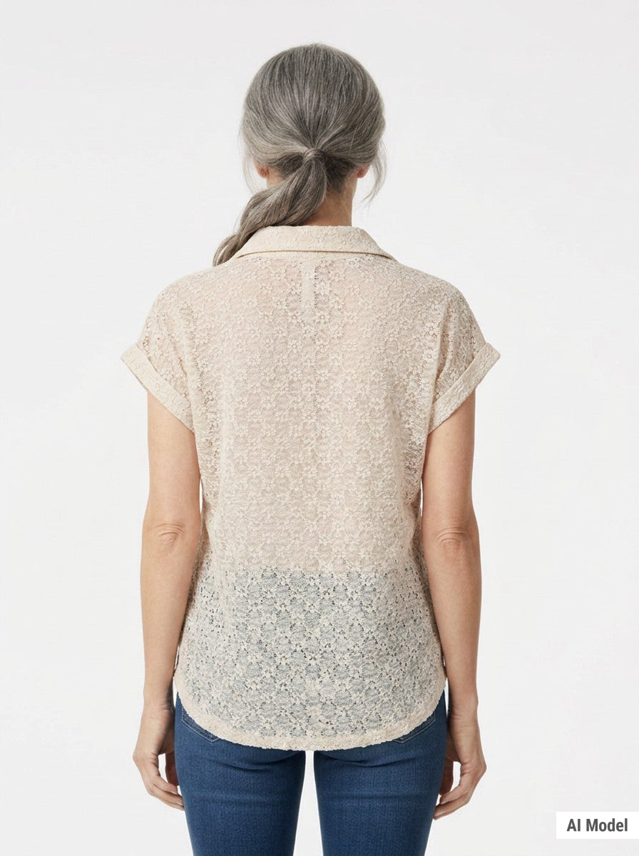 Back view of a woman with gray hair wearing a blush floral lace collared blouse with cuffed cap sleeves over blue jeans.